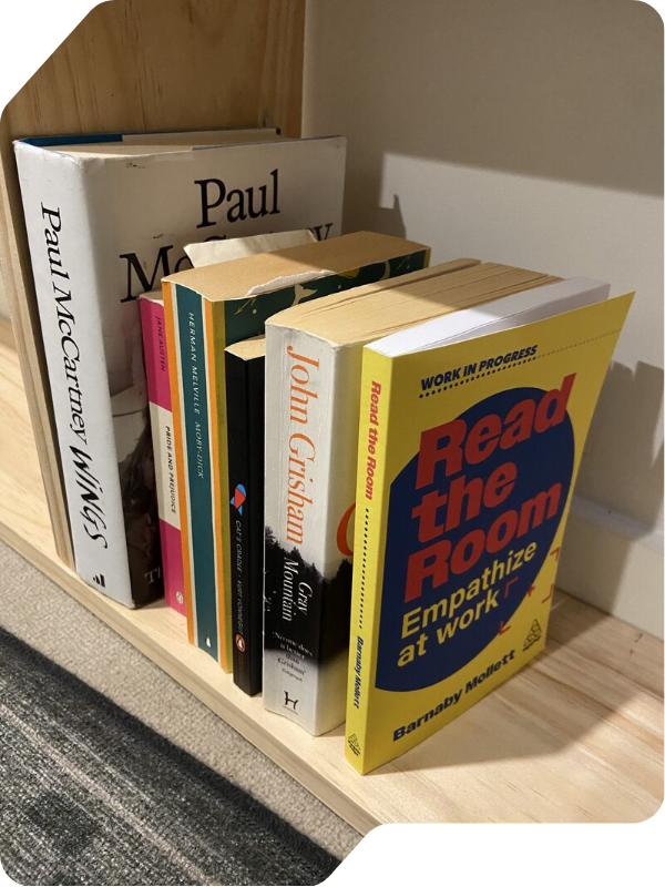 Stack of colorful books on a wooden shelf, including “Read the Room” ... and “Paul McCartney Wings.”